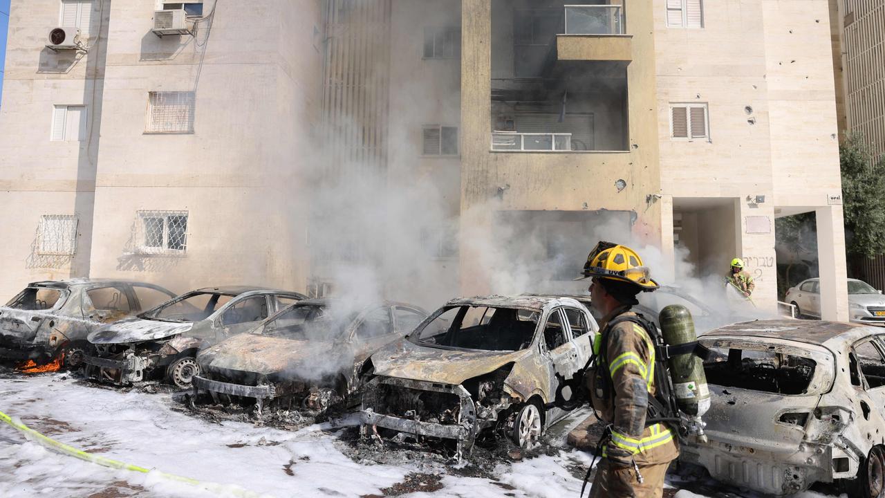 Israeli fire brigade teams douse the blaze in a parking lot outside a residential building following a rocket attack from the Gaza Strip in the southern Israeli city of Ashkelon. Picture: Ahmad Gharabli / AFP