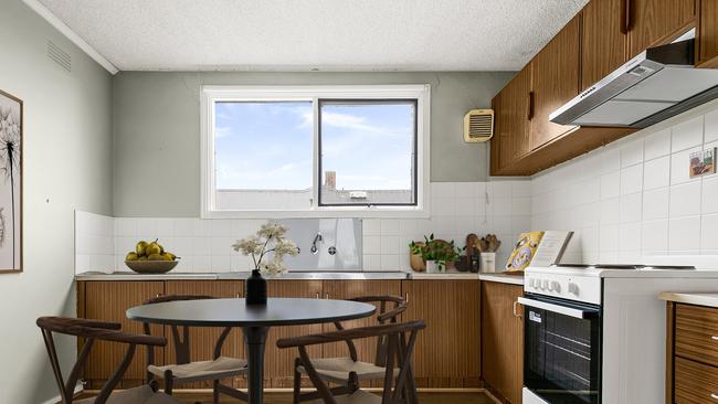 The kitchen has an upright electric stove and overhead storage.