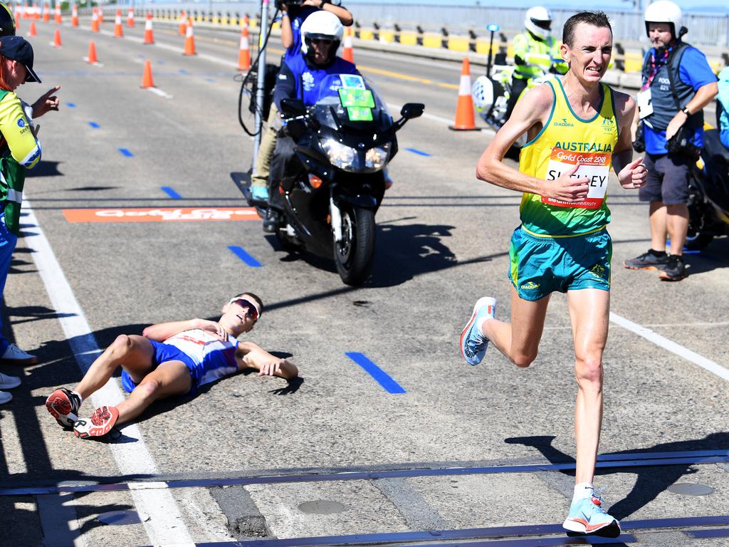 Michael Shelley (R) passes Callum Hawkins (L) after he collapsed less than 2km from the finish line. Shelley won the gold in the Marathon final. Picture: AAP Image/Tracey Nearmy