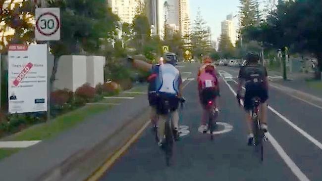 A cyclist points to the speed limit sign