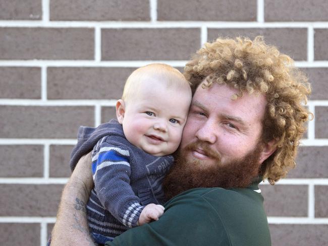 Toowoomba Dad Jeremi Simpson poses for a photograph with his son 7 month old Kaiden at home in Toowoomba, Saturday May 19, 2018. Jeremi is being hailed as a hero after taking down a knife wielding robber at Woolworths. (AAP/Image Sarah Marshall)