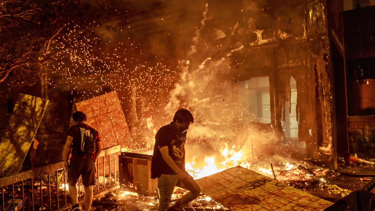 Protesters walk past burning debris outside the a police station in Minneapolis. Picture: Kerem Yucel / AFP.