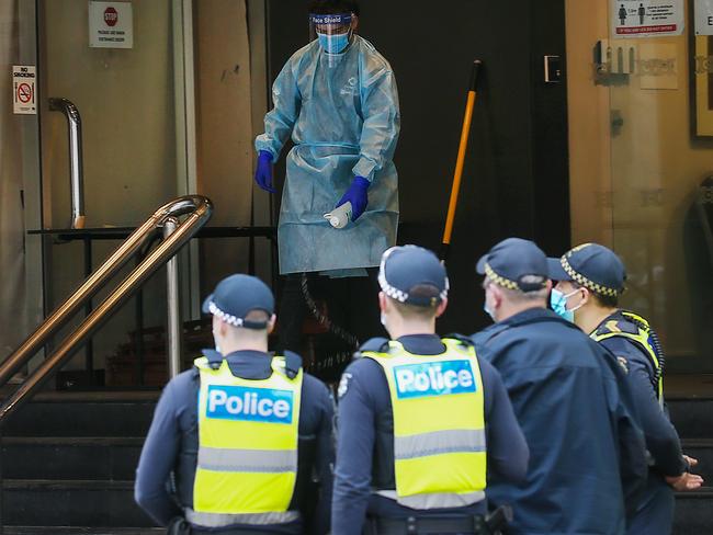 Hotel Grand Chancellor in Lonsdale St. Melbourne is being used as a quarantine hotel. A man decontaminates the steps after a young woman who walked out was taken away by paramedics. Picture: NCA NewsWire / Ian Currie