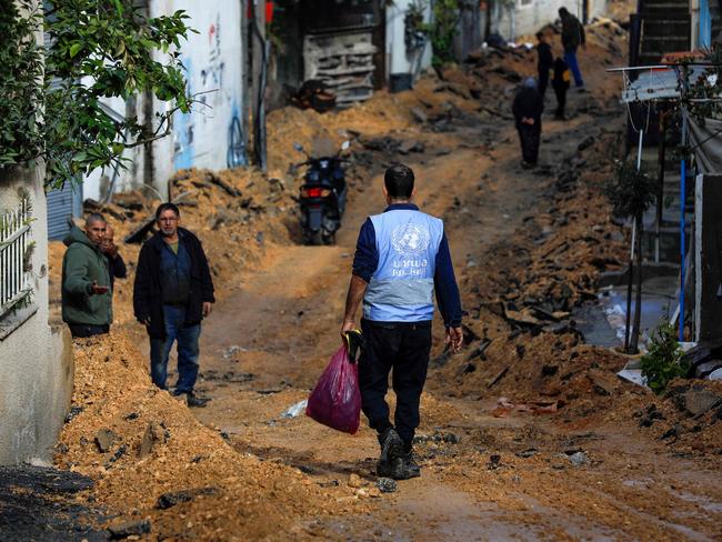 TOPSHOT - A man wearing a jacket of the UN agency for Palestinian refugees (UNWRA) walks on a street which has been bulldozed by the Israeli forces during a raid in Jenin in the occupied West Bank on January 29, 2024. (Photo by Zain JAAFAR / AFP)