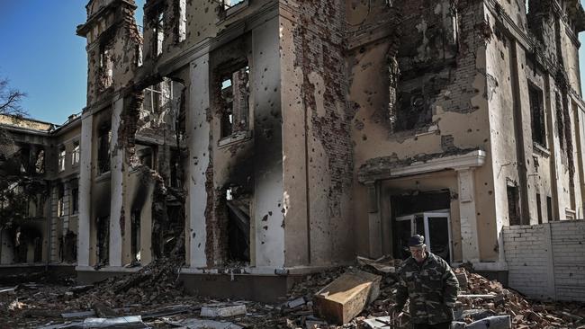 An elderly man walks in front of a destroyed school in Kharkiv. Picture: AFP