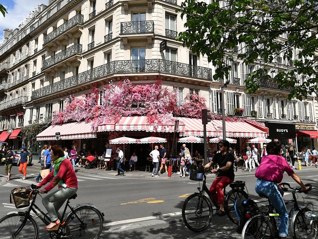 Paris, France-05 21 2022: Walking people and bicycles passing in front of a decorated cafÃƒÂ© terrace on rue de Rivoli in the Marais district of Paris, France.Escape 21 July 2024Cover story - ParisPhoto - iStock