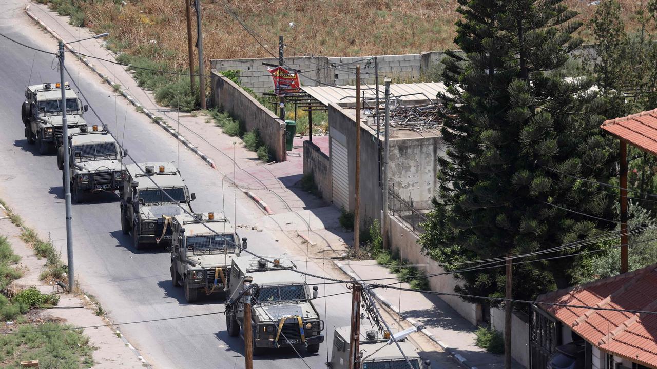 Israeli military armoured vehicles advance on a road during an operation in Jenin city in the occupied West Bank, on July 3, 2023. (Photo by RONALDO SCHEMIDT / AFP)