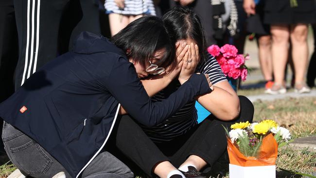 Sun Pacific College students lay flowers at a memorial for Chinese student Ping Wang, who was struck by a car and killed south of the Kewarra Beach roundabout on the Captain Cook Highway. Ping Wang's mother Junfang Yang mourns the loss of her daughter, comforted by student Mengjia Zuo (left), who was with Ms Wang at the time of her death. PICTURE: BRENDAN RADKE