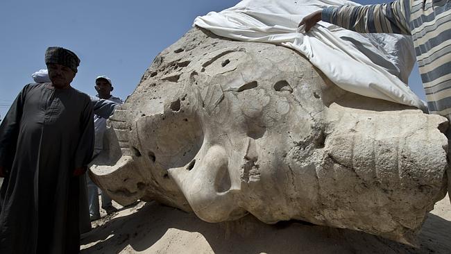 Mindful restoration ... Egyptian archaeological workers stand next to a newly displayed alabaster head from an Amenhotep III. Picture: Khaled Desouki