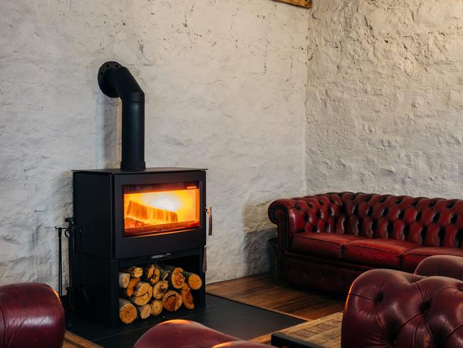 Triabunna Barracks’ cosy lounge, on the ground floor, with comfy Chesterfield couches and toasty cast iron woodfire with honesty bar featuring Tasmanian spirits, wines and beers. Picture: Adam Gibson