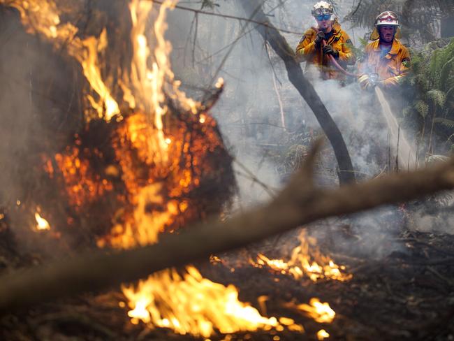 Geeveston volunteer firefighters Tomm Shepperd, left and Nathan Dowling extinguish a spot fire west of Geeveston. Picture: CHRIS KIDD