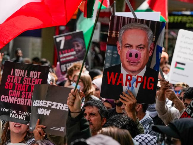 MELBOURNE, AUSTRALIA - OCTOBER 06: A general view as Pro-Palestine protesters waving Palestine flags as a protester holds a placard of Benjamin Netanyahu on October 06, 2024 in Melbourne, Australia. Organizers of pro-Palestine protests in Sydney are set to proceed with a rally on Sunday, October 6, despite legal attempts by police to prohibit the gatherings due to safety concerns related to anticipated crowd sizes and potential disruptions. The following day, a vigil is scheduled to honor victims of violence in Gaza, coinciding with the one-year anniversary of the Hamas attacks, which has drawn criticism from government officials who deem the timing "extremely provocative". Protesters also planned to gather for similar events in Melbourne. (Photo by Asanka Ratnayake/Getty Images)