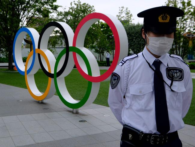 Security guards keep watch next to the Olympic rings in front of the HQ of the Japanese Olympic Committee in Tokyo. Picture: AFP