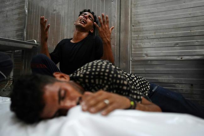 Palestinians mourn over the body of a relative killed in an Israeli strike, in southern Gaza's Khan Yunis