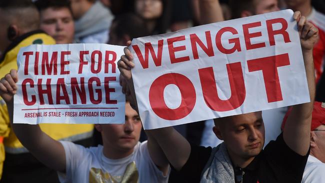 Arsenal fans hold up signs calling for the resignation of Arsenal's French manager Arsene Wenger after the English Premier League football match between Manchester City and Arsenal at the Etihad Stadium in Manchester, north west England, on May 8, 2016. / AFP PHOTO / PAUL ELLIS / RESTRICTED TO EDITORIAL USE. No use with unauthorized audio, video, data, fixture lists, club/league logos or 'live' services. Online in-match use limited to 75 images, no video emulation. No use in betting, games or single club/league/player publications. /