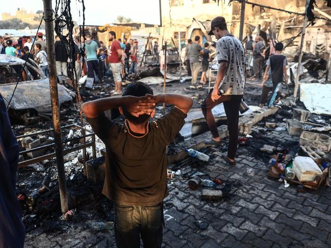 EDITORS NOTE: Graphic content / TOPSHOT - A Palestinian boy gestures as people check the destruction following an Israeli army strike around tents for displaced people inside the walls of Al-Aqsa Martyrs Hospital in Deir al-Balah, in the central Gaza Strip, on October 14, 2024 amid the ongoing war between Israel and Hamas.  (Photo by Eyad BABA / AFP)