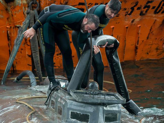 Spanish Civil Guard divers stand over the refloated prow of a submarine used to transport drugs illegally in Aldan, northwestern Spain, on November 26, 2019. - Police in Spain have seized a submarine, about 20 metres (65 feet) long, loaded with several tonnes of cocaine off the coast of the northwestern region of Galicia which arrived from South America, officials said today. Two Ecuadorian men were arrested as part of the operation yesterday in the seaside town of Cangas near the border with Portugal. (Photo by Lalo R. Villar / AFP)