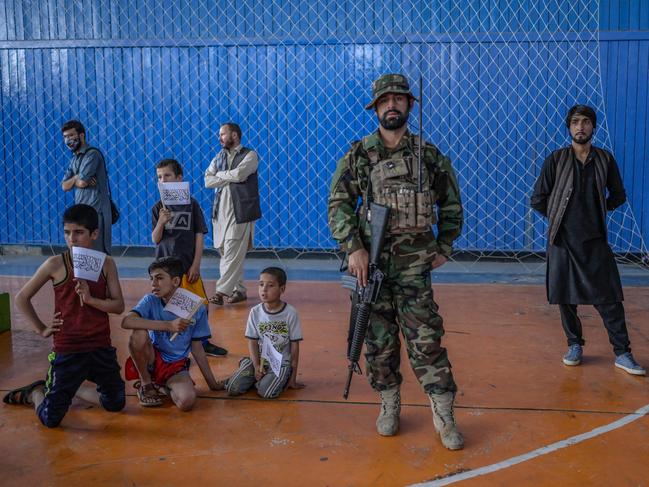 A Taliban fighter stands as youths wait to show their skills during an event organised for the visit of Taliban's director of physical education and sports. Picture: AFP