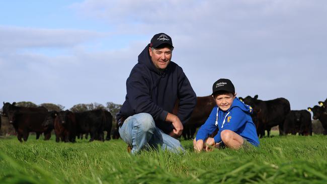 Farmer Jarrod Carroll with his son Hamish amid the lush green grass that has sprung to life just in time to save his herd of black angus. Picture: Charlie Peel