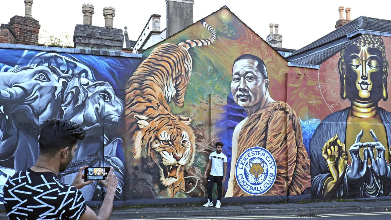 A man takes a photo near a mural of Leicester City's owner, Thai billionaire Vichai Srivaddhanaprabha near the Leicester City Football Club after a helicopter crashed in flames the day before.