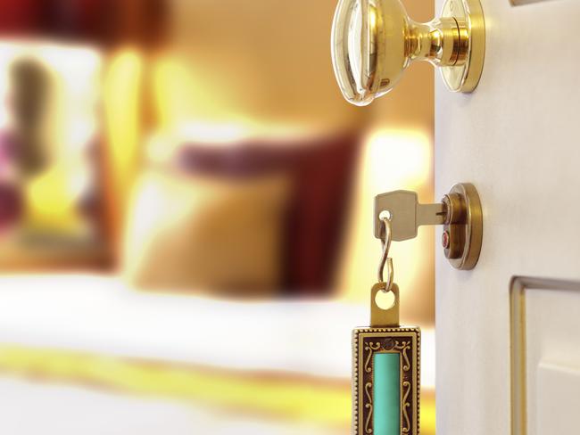 Hotel room or apartment doorway with key and keyring key fob in open door and bedroom in background