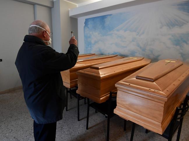 Italian priest, Don Giuseppe Locattelli, blesses coffins of the dead. Picture: AFP