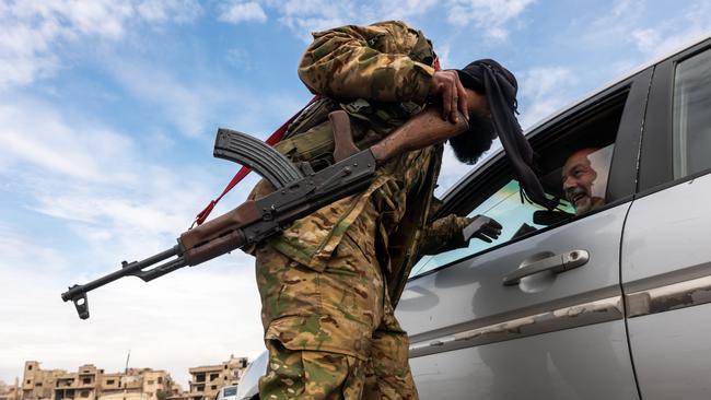 A HTS fighter checks identification at a checkpoint in the city of Homs on January 22. Picture: Spencer Platt/Getty Images