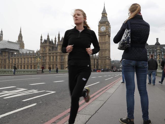 Pedestrians and a jogger cross Westminster Bridge with the Houses of Parliament in the background in central London on Marhc 23, 2017 after it reopened following its closure by security services during and after the March 22 terror attack. Picture: AFP