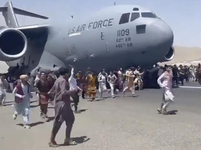 People run on tarmac of Kabul international airport as a US military aircraft attempts to take off.