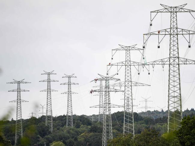 General view taken as workers of electricity transmission operator TransnetBW assemble a 380-KV power line on a high-voltage power pole near Pforzheim, southern Germany, on August 3, 2023. TransnetBW operates the electricity transmission grid in Federal state Baden-Wuerttemberg and expands it with a new 12 kilometers long  high-voltage line near this city. (Photo by THOMAS KIENZLE / AFP)