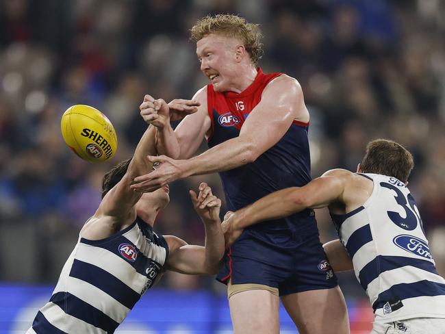 MELBOURNE , AUSTRALIA. May 4, 2024.  AFL. Melbourne vs Geelong at the MCG.   Clayton Oliver of the Demons tries to clear as he is tackled by 2 cats   . Pic: Michael Klein