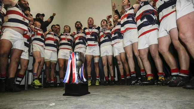 Highett’s players sing the song and admire the spoils after their grand final win.