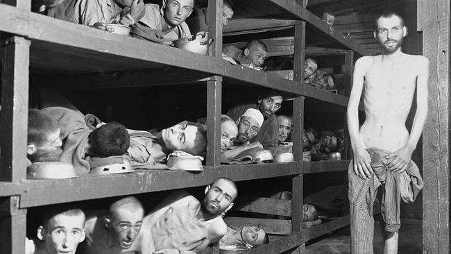 Former prisoners of the ‘little camp’ in Buchenwald stare out from the wooden bunks in which they slept three to a ‘bed’.