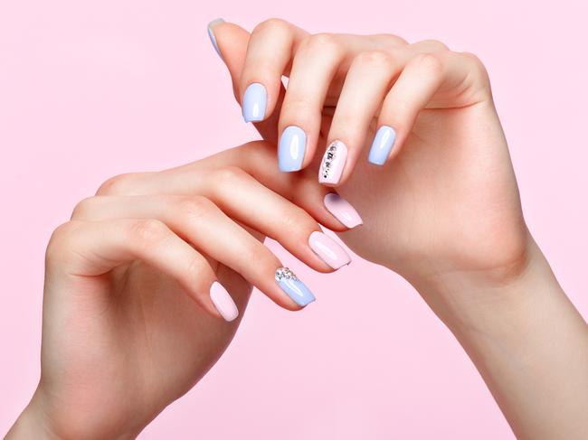 Beautiful pink and blue manicure with crystals on female hand. Close-up. Picture taken in the studio