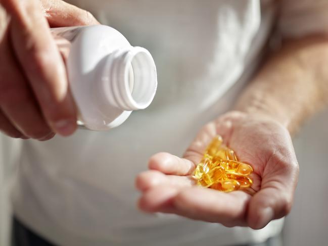 Bottle of omega 3 fish oil capsules pouring into hand