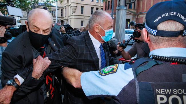 Peter and Paul Dawson are restrained by police after a scuffle with media as they leave the Supreme Court, Sydney, on Tuesday following the guilty verdict against their brother Chris. Picture: Justin Lloyd