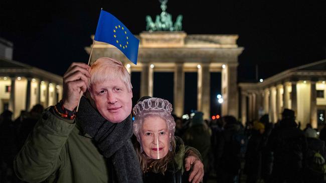 A couple wearing masks of Britain's Prime Minister Boris Johnson and Britain's Queen Elizabeth II wave an EU flag during a flashmob to mark Brexit in front of Berlin's Brandenburg Gate. Picture: AFP