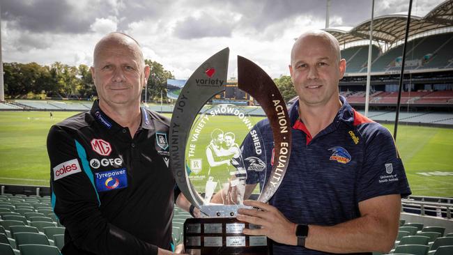 Port Adelaide Football Club Coach Ken Hinkley and Adelaide Football Club Coach Matthew Nicks hold the Showdown Trophy, which features the iconic image of the Bond brothers. Picture: Emma Brasier