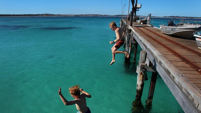 Young boys jump off Vivonne Bay Jetty into the water. Picture: Lisa Maree Williams/Getty Images
