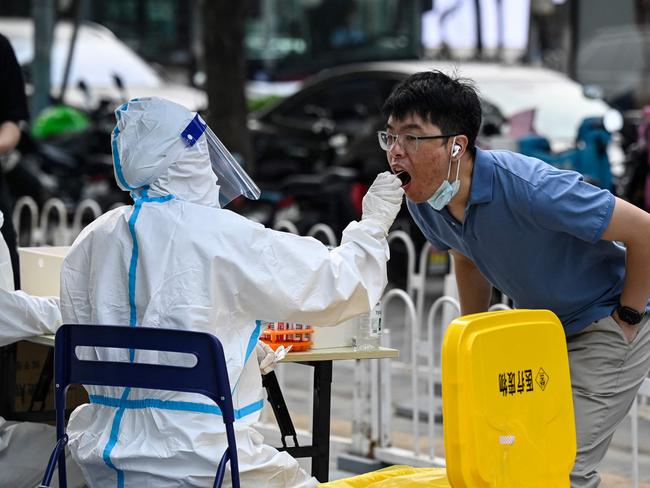 A health worker gets a swab sample from a man to be tested for Covid-19 at a nucleic acid testing station in Beijing in June. Picture: AFP