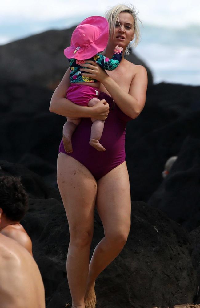 Katy Perry shows off curves in purple swimsuit as she holds baby