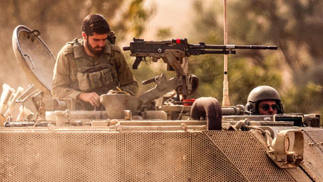 An Israeli army soldier puts on his helmet as he mans a turret in an armoured tracked vehicle along the border with the Gaza Strip in southern Israel. Picture: AFP