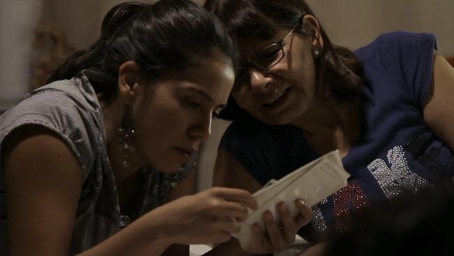 Filmmaker Lissette Orozco looks at photos from the past with her aunt Adriana Rivas in a scene from the documentary Adriana’s Pact.