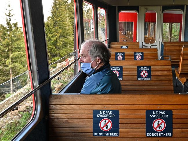 Social distancing markers with the lettering 'Do not sit here' are seen on seats as a tourist sits on the red railway train of Montenvers near Chamonix Mont-Blanc, eastern France. Picture: AFP