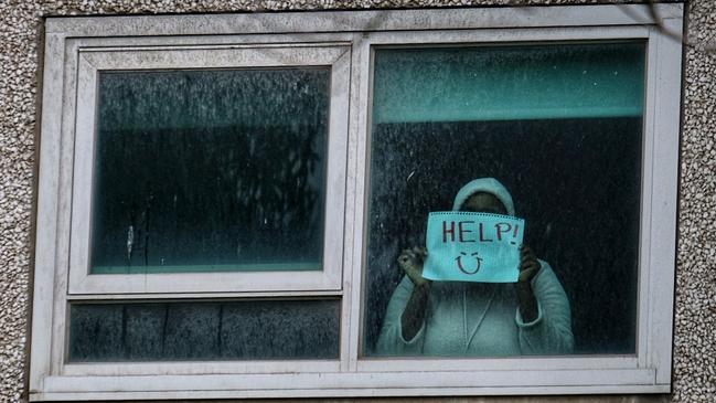 A woman holds a sign on the first day of the lockdown at the North melbourne housing commission flats on Sunday. Picture: Luis Enrique Ascui