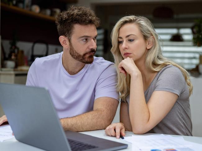 Young couple checking their home finances and looking worried while looking at their bank statements online; money budgeting stress banking generic