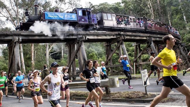 Runners on Belgrave-Gembrook Rd, Belgrave as Puffing Billy crosses the trestle bridge. Picture: Mike Keating.