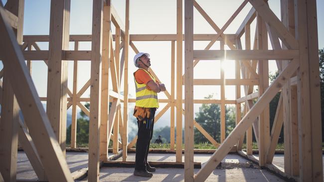 Shot of a senior builder working on wooden house in nature.