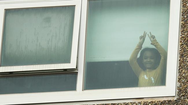 A young resident of the Alfred Street tower gestures before the lockdown is lifted. Picture: NCA NewsWire/Daniel Pockett