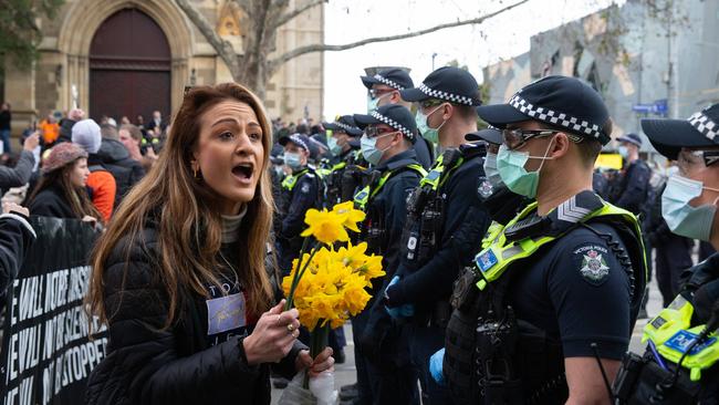 A women tries to hand out daffodils to the police line at the protest. Picture: Sarah Matray / NCA NewsWire